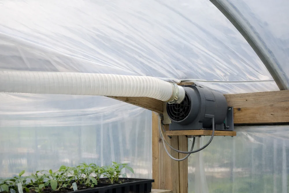 Inflation blower maintaining air pressure between two layers of greenhouse plastic in a commercial hoop house