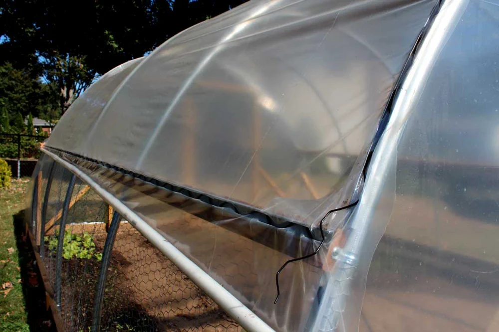 Close-up of wiggle wire securing greenhouse poly film into a lock channel on a hoop house frame
