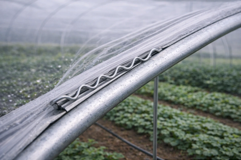 Close-up of wiggle wire locking greenhouse plastic film into an aluminum lock channel