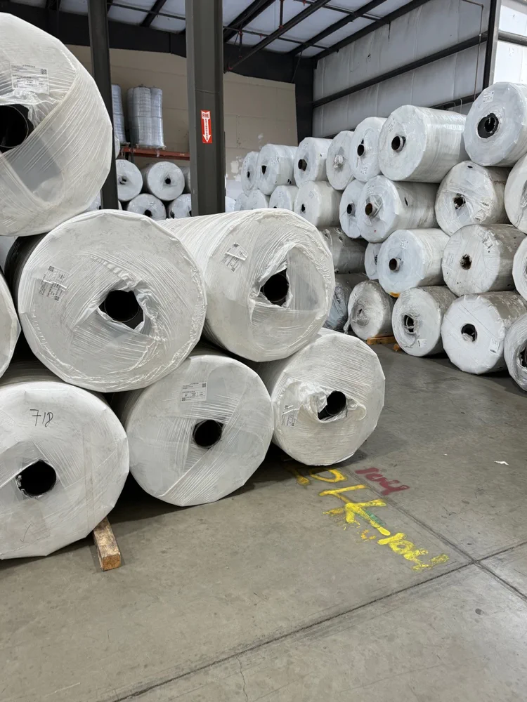 Close view of stacked greenhouse plastic master rolls inside a warehouse