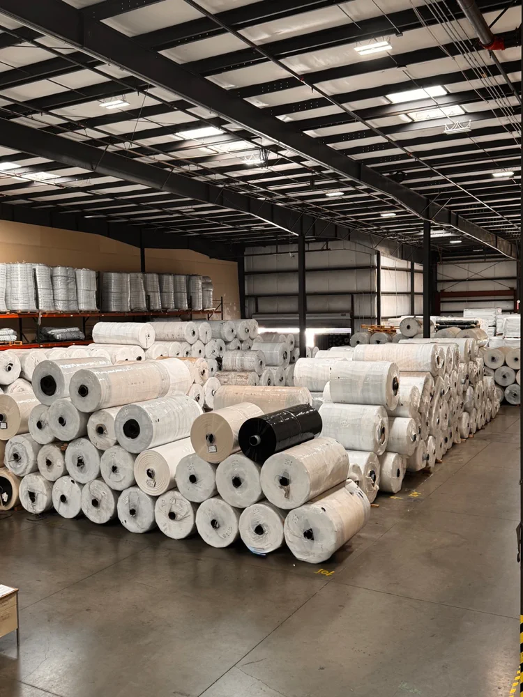 Rows of greenhouse plastic master rolls stored inside a warehouse